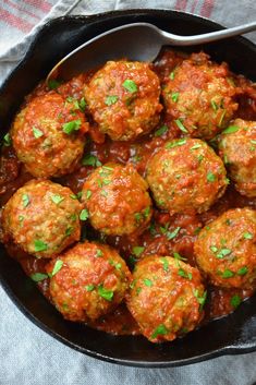 a skillet filled with meatballs covered in sauce and garnished with parsley