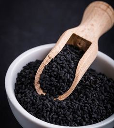 a bowl filled with black seeds and a wooden scoop