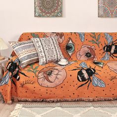 a couch covered in an orange and black flowered design with two bees on it