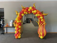 an arch made out of balloons in the middle of a room with tables and chairs