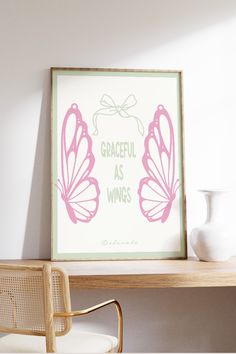 a pink and green butterfly art print on a white wall above a desk with a chair