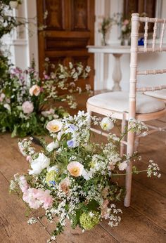 a bouquet of flowers sitting on top of a wooden floor next to a white chair