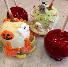 three decorated apples sitting next to each other on top of a marble counter with candy sticks sticking out of them