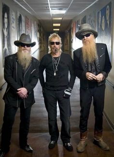 three men with long beards and hats standing next to each other in an hallway