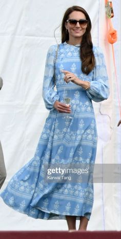 a woman in a blue dress holding a drink