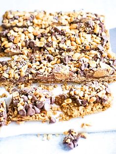 two pieces of granola bar sitting on top of a white cutting board with chocolate chips