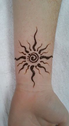 a hand with a tattoo on it that has a sun and swirls in the middle