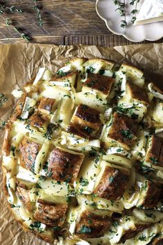 a pie with cheese and herbs on it sitting on top of a piece of wax paper