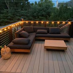 a couch sitting on top of a wooden deck next to a table and lights hanging from the ceiling