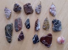 many different types of rocks on a wooden table with wire wrapped around them and hanging from hooks