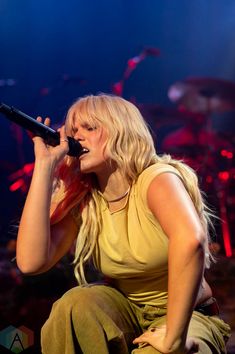 a woman sitting on top of a stage holding a microphone