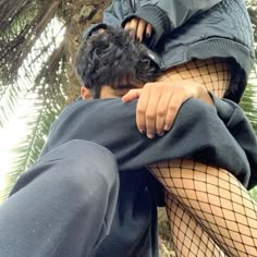 a man in fishnet tights is hugging a woman's head with her arms around him