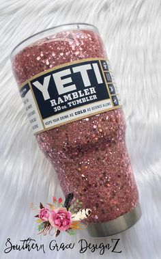 the yeti tumbler is pink glitter and has a flower on it's side