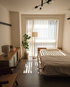 a bed sitting in a bedroom next to a window with blinds on the windowsill