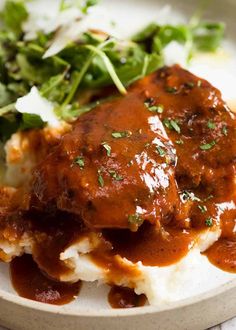 a white plate topped with mashed potatoes covered in gravy and garnish