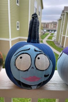 three painted pumpkins sitting on top of a wooden bench