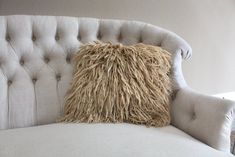 a white couch with a fluffy pillow on it's back and the seat upholstered