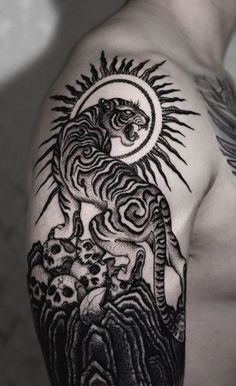 a man with a tattoo on his arm and shoulder is holding a tiger in the sun