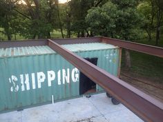 a green shipping container with the word shipping painted on it's side and an open door