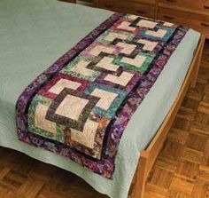 a bed with a quilt on top of it in the middle of a wooden floor