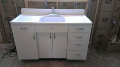 a white sink sitting on top of a wooden floor next to a wall under construction