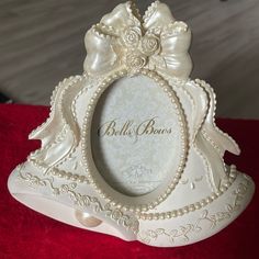 a white photo frame with pearls and bows on it sitting on a red tablecloth