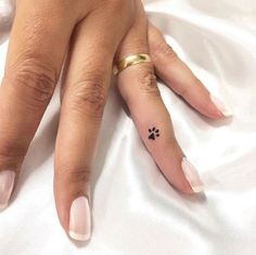 a woman's hand with a small black flower tattoo on her left ring finger