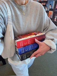 a person holding three books in their hands