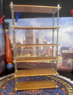 three tiered shelving unit on rug in front of wall with cityscape