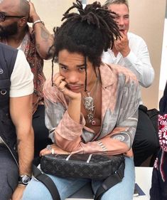 a man with dreadlocks sitting in front of other people