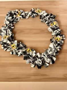 an origami wreath made out of books on a wooden surface with yellow and black flowers