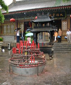 a group of people standing in front of a building with red sticks sticking out of it