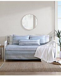 a blue and white striped couch sitting in a living room next to a round mirror