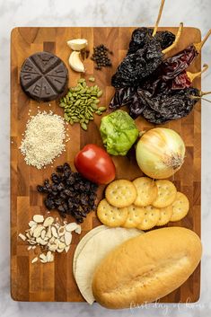 a wooden cutting board topped with different types of vegetables and crackers on top of it