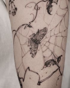 a woman's thigh with a spider web and butterfly tattoo on the side of her leg