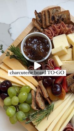 a cheese board with grapes, meats and bread