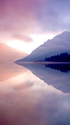 the sky is reflecting in the still water on the lake's shore as the sun goes down