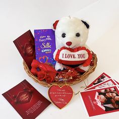 a teddy bear sitting in a basket with valentine's day cards and greetings