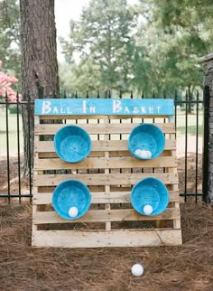 a wooden pallet with blue plates on it in front of a tree and fence