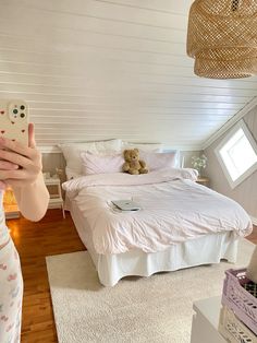 a woman taking a selfie in front of her bed with a teddy bear on it