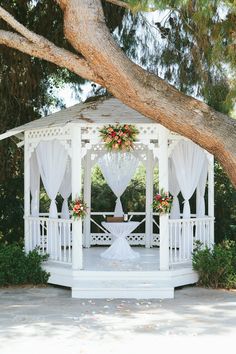 a white gazebo with curtains and flowers on it