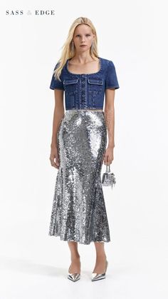 a woman in a silver sequin skirt and denim shirt standing on a white background