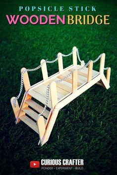 a wooden bridge sitting on top of a green grass covered field with chains hanging from it's sides