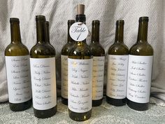 six bottles of wine are lined up on a tablecloth with the names of their wines