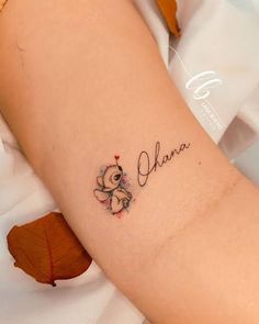 a small tattoo on the arm of a girl that reads,'ohana '