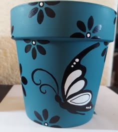 a blue flower pot with a butterfly painted on it