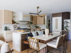 an open kitchen and dining room area with white counter tops, beige chairs, and wooden cabinets