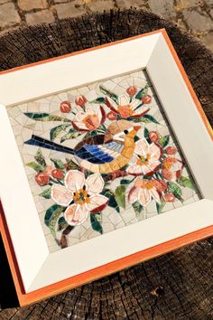 a bird sitting on top of a piece of wood next to a flowered design