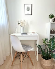 a white desk and chair in a small room with potted plants on the side