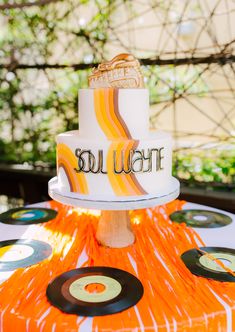 a white and orange cake sitting on top of a table covered in vinyl record records